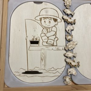 Insert couvercle bois trofast pêcheur sur ponton avec canne à pêche et poissons